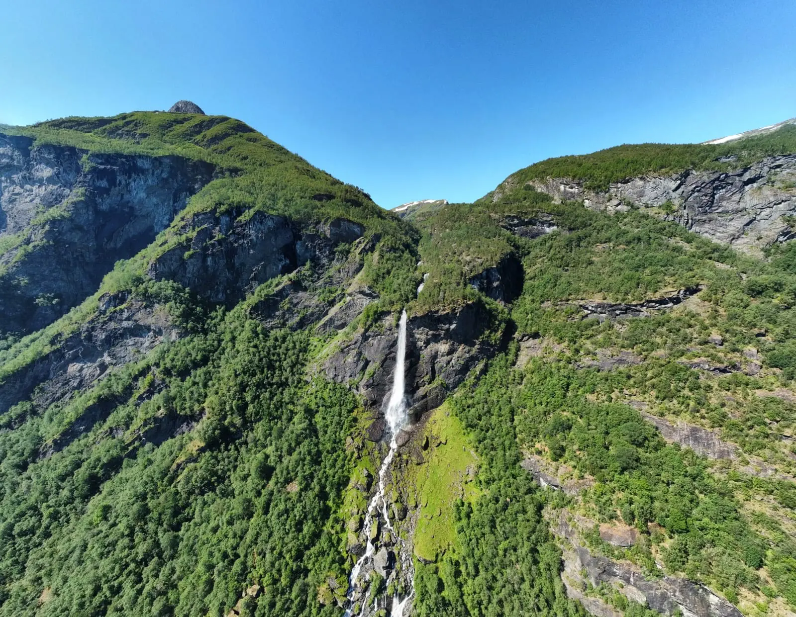 Vue aérienne d’une haute cascade dévalant une montagne verdoyante