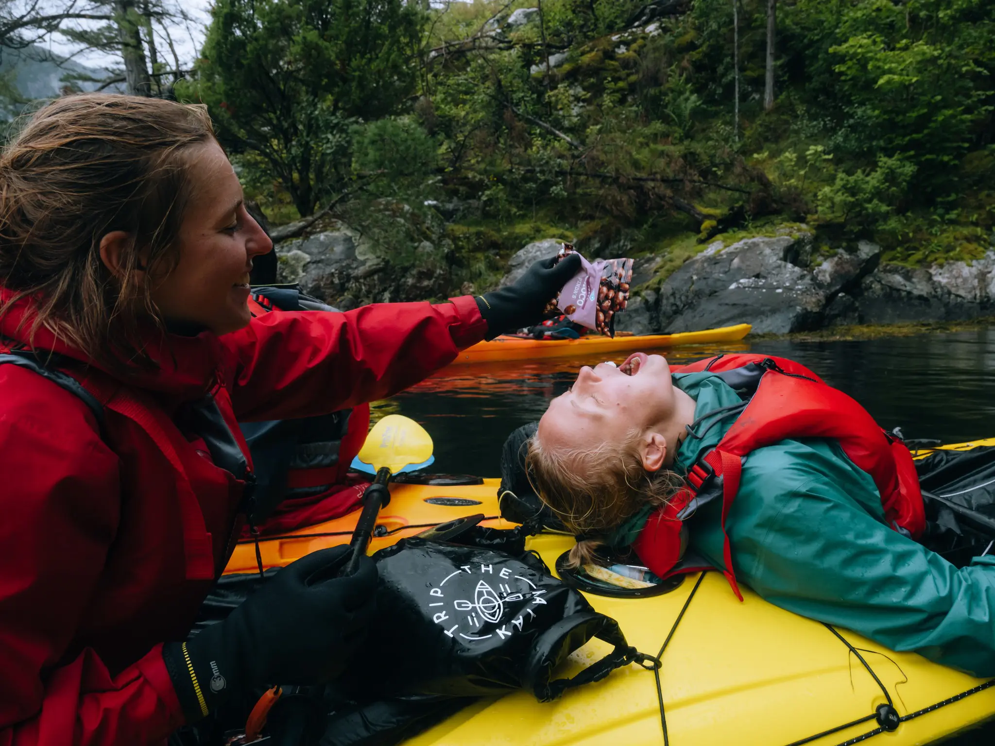 deux femmes en kayak, l’une donnant des en-cas à l’autre