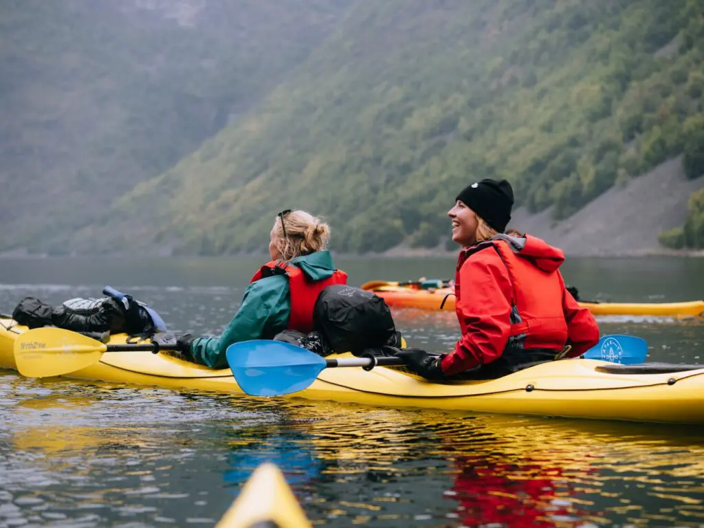 deux femmes faisant du kayak sur un lac entouré de montagnes