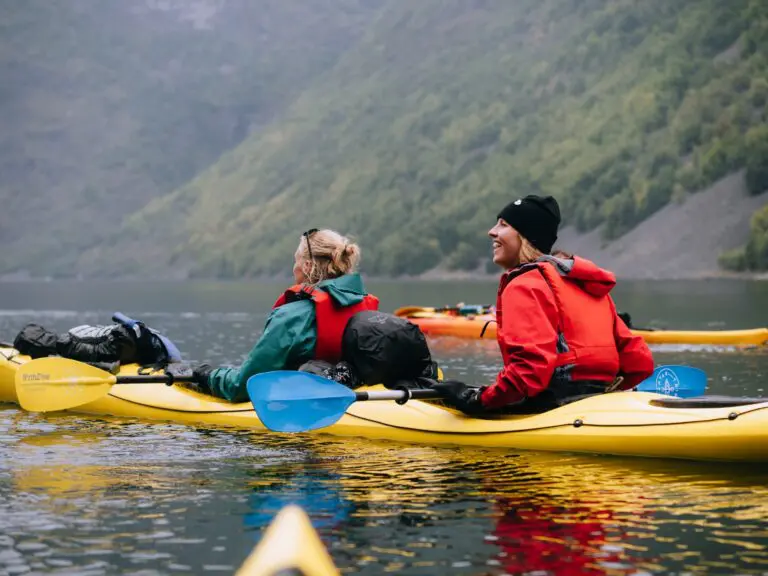 deux femmes faisant du kayak sur un lac entouré de montagnes
