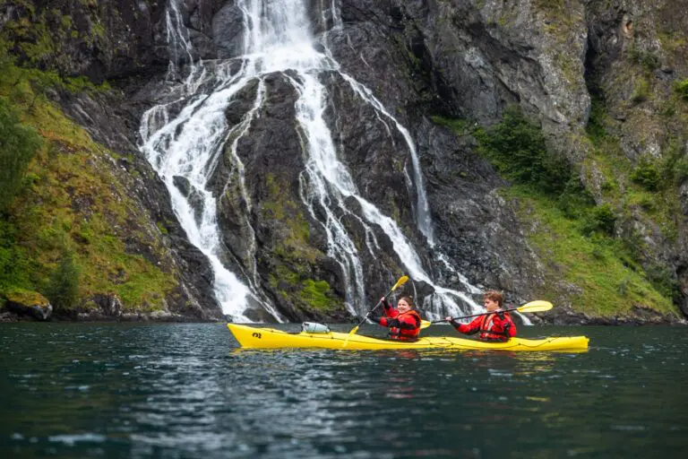 deux personnes faisant du kayak devant une grande cascade