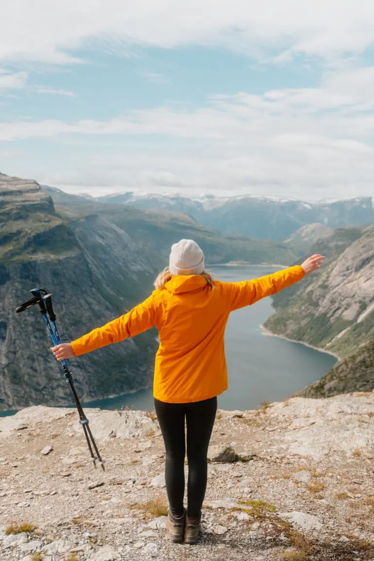 hiker with arms outstretched overlooking a Norwegian fjord