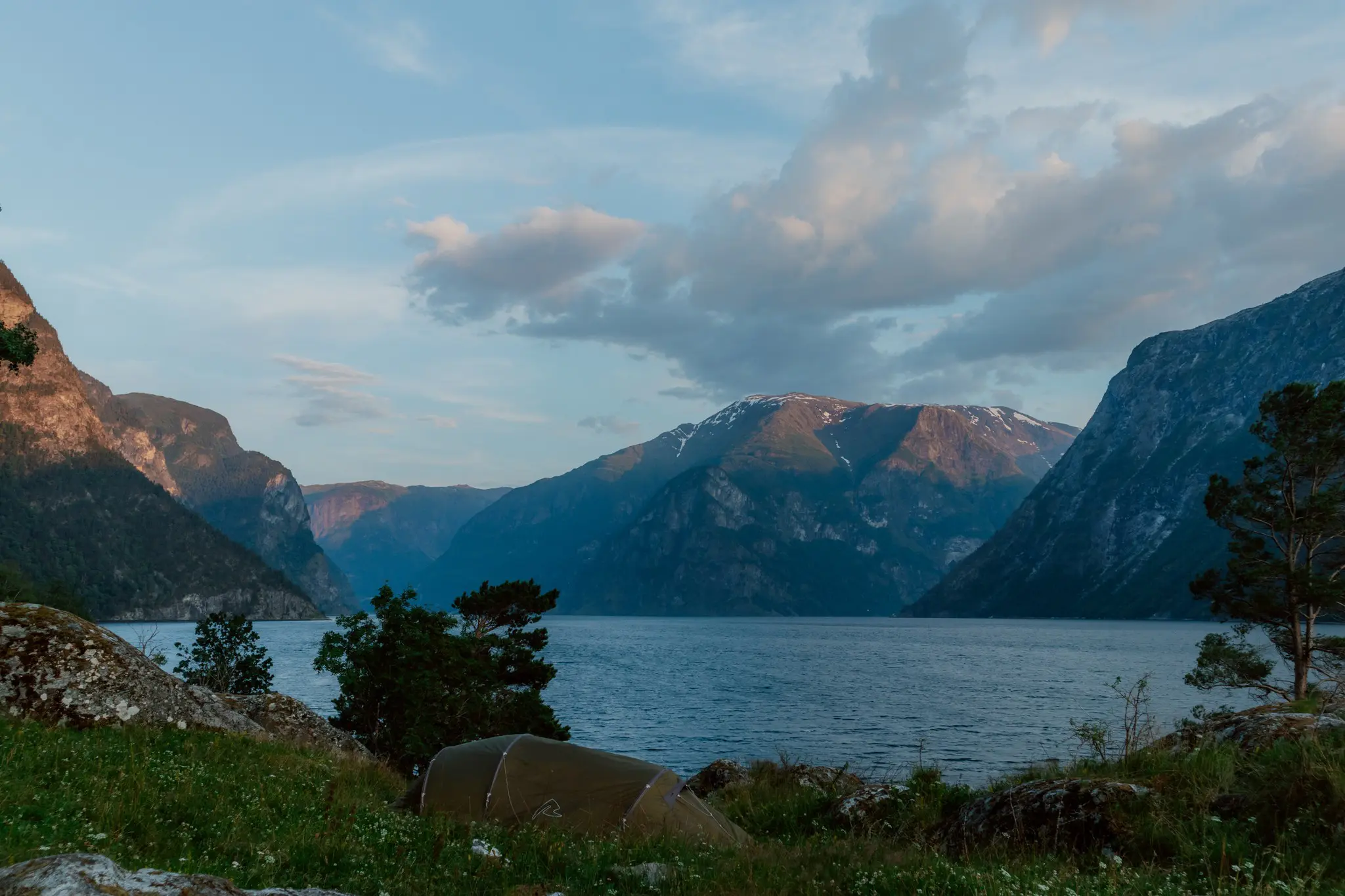 tente installée près d’un fjord en Norvège au coucher du soleil