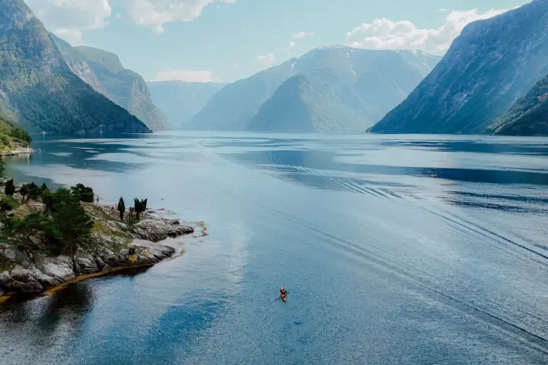 kayakiste pagayant sur un vaste fjord entouré de montagnes