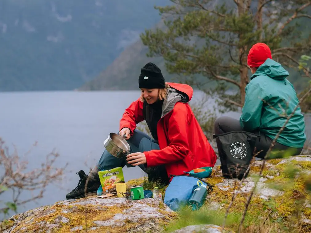 Woman boiling water for coffee and a food pack - kayaking - Norway fjord - hiking in Norway - kayaking - from Brussels airport