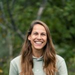 smiling woman in Travelbase hoodie outdoors