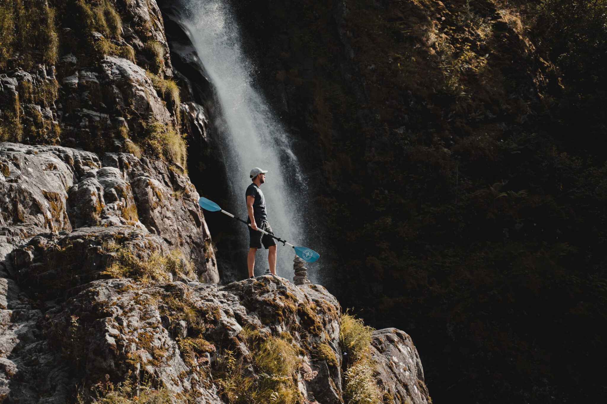 Men with paddle next to waterfall - Kajakken - Noorwegen fjord - wandelen in Noorwegen - kayaking - vanaf luchthaven Brussel